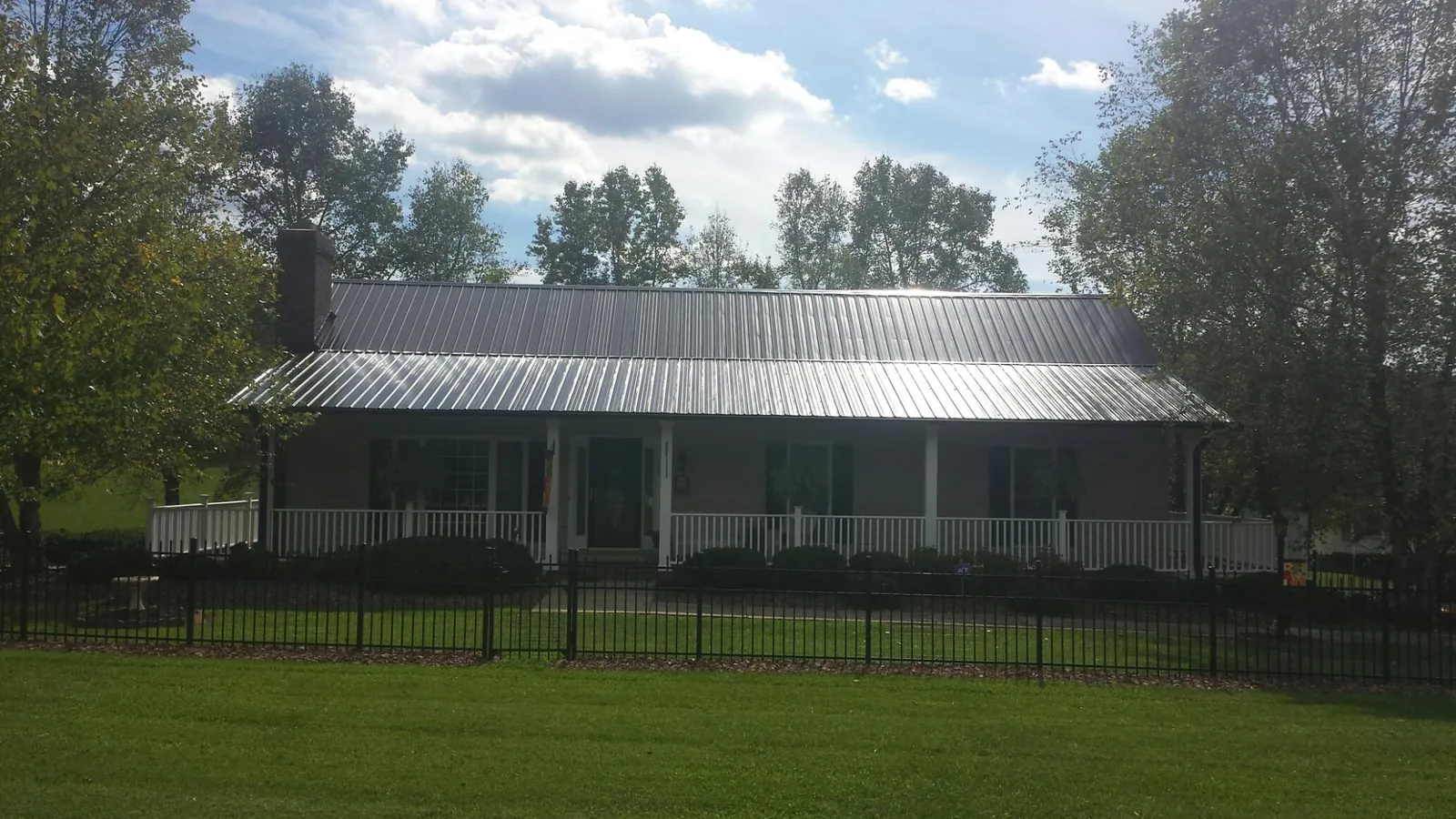 Gray metal roof on a brick ranch with a full width front porch — Gutter Guard Installation work by our crew in West Newton